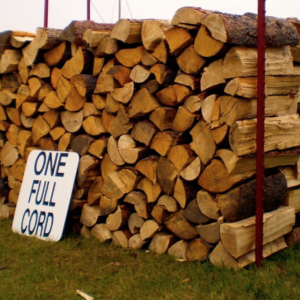Description A full cord of firewood is 128 cubic feet of tightly stacked wood — the volume of a stack 4 feet high, 4 feet deep and 8 feet long. That measurement is defined by statute in most US states, so a cord should mean the same amount no matter who delivers it. Chimney Monkey no longer sells or delivers firewood. We have kept this page up because so many people arrive here looking for straight answers about cord sizes, weight and seasoning — and because the wood you burn has a direct effect on how much creosote ends up in your chimney. What is the difference between a full cord and a face cord? A full cord measures 4 by 4 by 8 feet. A face cord, sometimes called a rick or a rack, is still 4 feet high and 8 feet long but only one log deep, usually about 16 inches. That works out to roughly one third of a full cord, so always ask how deep the stack is before agreeing on a price. How much does a full cord of firewood weigh? Weight depends far more on species and moisture than on volume. A seasoned cord of dense hardwood such as oak, hickory or maple generally falls between about 3,000 and 4,500 pounds. Softwoods like pine are considerably lighter, and freshly cut green wood can weigh well over a ton more because of the water still trapped inside it. How long does a full cord of firewood last? For a household that lights a fire on weekends and holidays, a full cord often covers a whole winter. If a fireplace or wood stove is your main heat source, expect to work through a cord in roughly four to eight weeks of cold weather. Open masonry fireplaces consume wood fastest because most of the heat escapes up the flue. How can you tell if firewood is properly seasoned? Seasoned firewood has dried to below roughly 20 percent moisture, which usually takes six to twelve months and closer to two years for dense oak. Look for cracks radiating across the end grain, a faded gray-brown color, loose bark, and a light feel for its size. Knock two pieces together: seasoned wood gives a sharp hollow crack while wet wood makes a dull thud. How should you stack and store a cord of firewood? Keep the stack off the ground on pallets or rails, cover only the top so rain runs off while the sides stay open to the wind, and leave a gap between the woodpile and the house to discourage insects and rodents. Bring no more than a few days worth indoors at a time. Wood sealed in a shed, or under a tarp that reaches the ground, holds moisture in rather than letting it out. Why does your firewood choice matter for your chimney? Burning unseasoned or resinous wood at low temperatures is the quickest way to build creosote, the tarry deposit behind most chimney fires. Dry hardwood burned hot leaves far less behind. Whatever you burn, NFPA 211 calls for a chimney inspection every year, and a sweep once deposits start to build.
